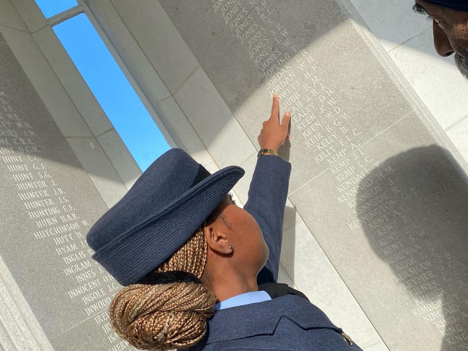 Personnel points to name on memorial. 